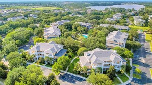 A residential area with multiple houses, a swimming pool, and a lake in the background. - 2nd Floor Condo w/ Basketball Court, Restaurant, Balcony, Gym, Near Theme Parks (Davenport)