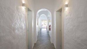 A hallway with white walls, a tiled floor, and two doors with light fixtures. - Casa Oliva Refúgio Rural Contemporâneo (Salvada)
