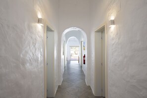 A hallway with white walls, a tiled floor, and two doors with light fixtures. - Casa Oliva Refúgio Rural Contemporâneo (Salvada)