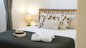 A neatly made bed with a wooden headboard, a lamp, and a hat on the bed. - Casa Oliva Refúgio Rural Contemporâneo (Salvada)