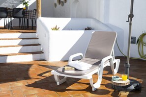 A sun lounger with a cushion, a book, a glass of orange juice, and a bowl of blueberries on a wooden stool. - Casa Oliva Refúgio Rural Contemporâneo (Salvada)