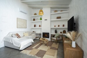 A modern living room with a fireplace, white walls, and a television. - Casa Oliva Refúgio Rural Contemporâneo (Salvada)