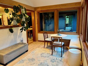 A cozy room with a bench, a table, chairs, and a large window. - Valhalla Cottage, hunters or skiers dream! Slocan Valley’s sweet spot! (Central Kootenay H)