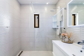 Ein Badezimmer mit Dusche, Waschbecken und Spiegel, sowie einer Dekoration aus Kerzen und Blumen.