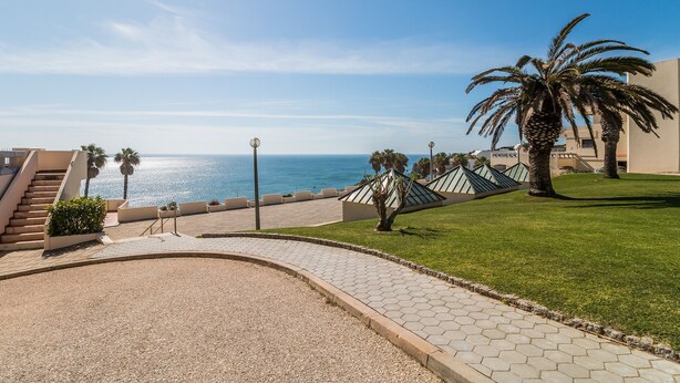 Un chemin pavé mène à un bâtiment d’où l’on a une vue sur la mer.