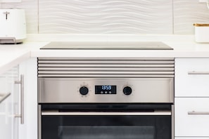 Une cuisine équipée d’un four encastré, d’une horloge numérique et d’un four à micro-ondes.