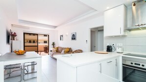 Une cuisine moderne dotée d’un îlot central, de meubles blancs et d’un four encastré.