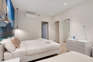 A bedroom with a bed, bedside tables, a dresser, an air conditioning unit, and a door leading to another room. - Villa 'Andrea' with Lake View, Wi-Fi and Air Conditioning (Garda)