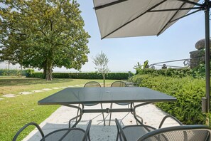 An outdoor patio with a metal table and chairs, surrounded by greenery and a view of the sea. - Villa 'Andrea' with Lake View, Wi-Fi and Air Conditioning (Garda)
