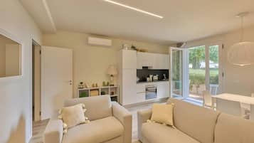 Un salon moderne comprenant deux canapés, une table à manger et un coin cuisine avec des appareils électroménagers intégrés.