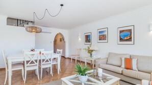 Un salon moderne comprenant un coin repas, un canapé et une table basse agrémentée d’une plante.