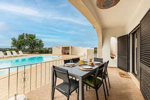 Ein Balkon mit Pool, Esstisch, Stühlen und Blick auf die Landschaft.