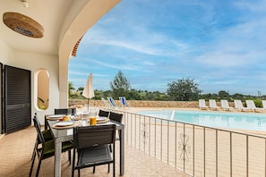 Ein Poolbereich mit Esstisch, Blick auf den Pool und Liegestühlen am Pool.