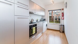 Eine moderne Küche mit Edelstahlgeräten, einer Waschmaschine und einem Fenster mit Blick auf Gebäude.