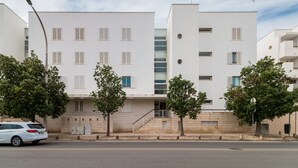 Ein modernes Gebäude mit flacher Fassade, zahlreichen Fenstern und einer Treppe, die zum Eingang führt.