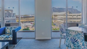 A balcony with a view of a mountainous landscape, a sofa, a chair, and a table. - Luxurious Accessible Apartment With Ocean Views in Kaapstad (Cape Town)