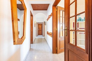A hallway with wooden doors and mirrors, leading to a room with a view. - Lagos Sea View | Near the City Center (Lagos)