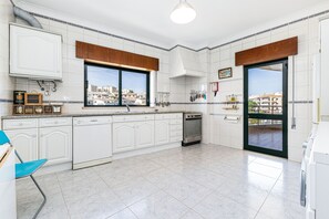 A modern kitchen with white cabinetry, a built-in oven, and a large window offering a city view. - Lagos Sea View | Near the City Center (Lagos)