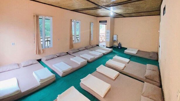 A room with multiple beds arranged in rows, a green carpet, and a wooden ceiling. - Cozzy Villa KC Cileunca (Bandung)
