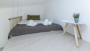 A bedroom with a bed, pillows, a bedside table with a plant, and a small round table. - Chilling Studio in Lagos (Lagos)