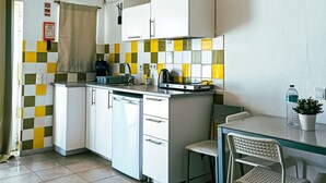 A compact kitchen with a dishwasher, a small dining area with a table and chairs, and a checkered backsplash. - Chilling Studio in Lagos (Lagos)