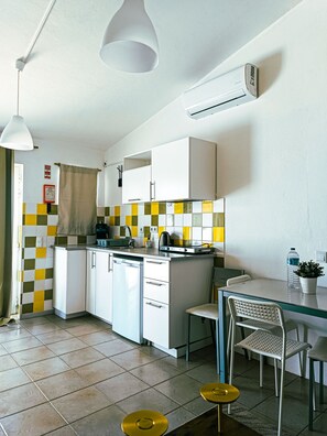 A compact kitchen with a dishwasher, a small dining area with a table and chairs, and a checkered backsplash. - Chilling Studio in Lagos (Lagos)