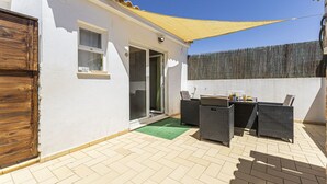 A patio with outdoor furniture, a sliding glass door, and a yellow shade sail. - Chilling Studio in Lagos (Lagos)