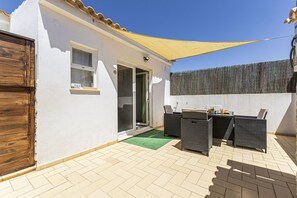 A patio with outdoor furniture, a sliding glass door, and a yellow shade sail. - Chilling Studio in Lagos (Lagos)