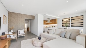 A modern living room with a sofa, a coffee table, and a dining area with a wooden table and chairs. - Ria Terrace House in Alvor (Alvor)