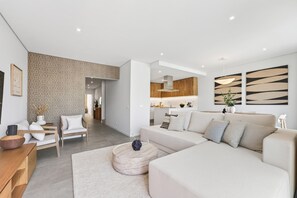 Ein modernes Wohnzimmer mit einer Couch, einem Couchtisch und einem Essbereich mit Holztisch und Stühlen.
