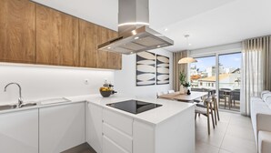 A modern kitchen with a central island, a built-in oven, and a large window overlooking a cityscape. - Ria Terrace House in Alvor (Alvor)
