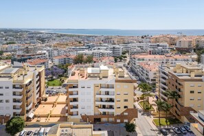 A coastal urban area with multi-story buildings, a beach in the distance, and a clear sky. - Casa Oliveira 31 in Lagos (Lagos)