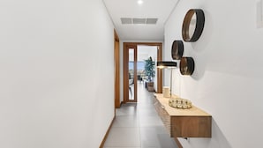 Un pasillo con suelo de madera, un accesorio de iluminación y un espejo instalado en la pared.