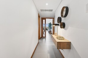 Ein Korridor mit Holzboden, einer Leuchte und einem an der Wand befestigten Spiegel.