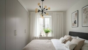 Una camera da letto con un letto, una finestra con tende, una pianta sul davanzale e una lampada a soffitto.