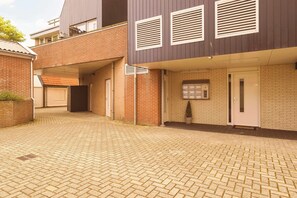 Ein modernes Gebäude mit Ziegelverkleidung, einem überdachten Eingangsbereich und einem gepflasterten Innenhof.