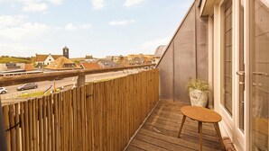 Un balcon avec un plancher en bois, une petite table et une plante en pot.