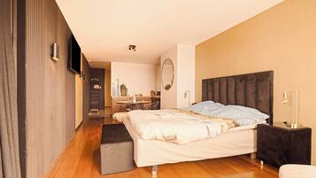 Un dormitorio moderno con una cama grande, una mesita de noche, un televisor de pantalla plana y un pequeño escritorio con silla.
