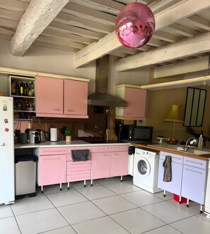 Eine Küche mit rosa Schränken, einer Waschmaschine, einer Mikrowelle und einem pinken Discokugel.