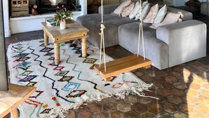 Un salon chaleureux avec une cheminée, un canapé, une table basse et des plantes suspendues.