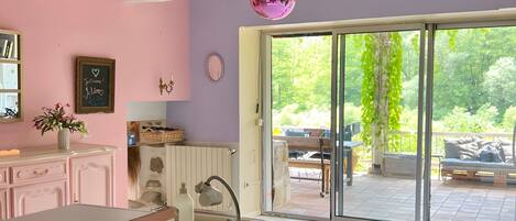 A kitchen with a large window, a pink disco ball, and a view of the outdoors.