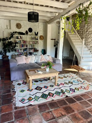 A cozy living room with a sofa, coffee table, and bookshelf, a staircase, and a patterned rug. - Holiday Home “Loft by the Water” with Private Terrace and Wi-Fi (Ucel)