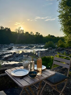 Ein Esstisch draußen mit Blick auf einen Fluss und Bäume.