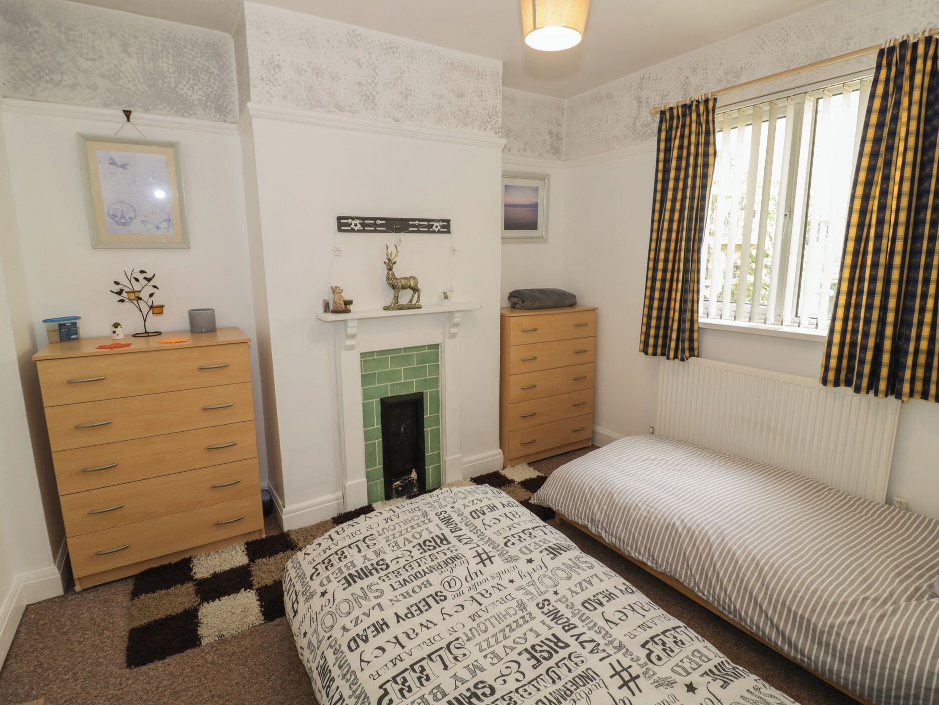 Un dormitorio con cama, cómoda y chimenea.