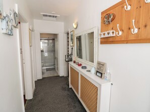A hallway with a shower, a mirror, a vanity with toiletries, and a wall-mounted coat rack. - Mount Joy (Leicester)