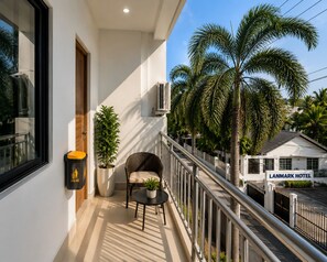 Ein Balkon mit einem Blumentopf, einem Stuhl und einer Mülltonne.