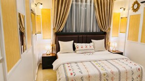 Hotelkamer met een groot bed, twee nachtkastjes, een raam met gordijnen en wandlampen.