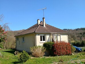 Una casa de una sola planta con techo de tejas, una chimenea y una antena parabólica.