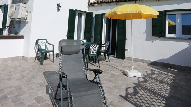 Un patio con una mesa, sillas y un paraguas amarillo.