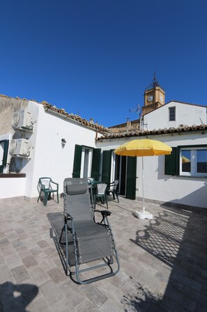 A patio with a table, chairs, and a yellow umbrella.